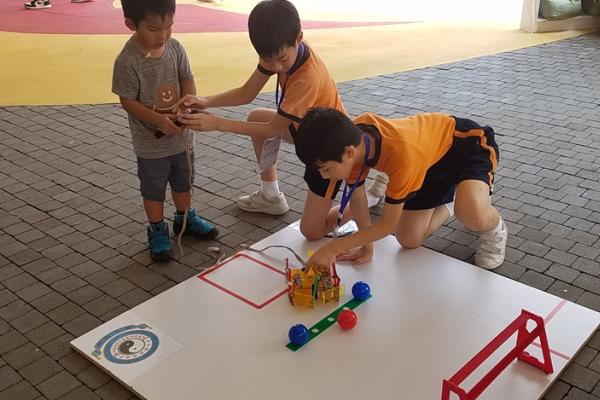 學生耐心地教導小朋友操控足球機械人。