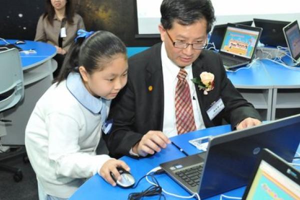 學生為湯修齊校董示範電子學習，一同體驗如何利用電子科技提升學習成效。