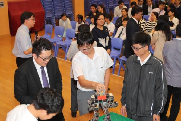 支援計劃  同學們向梁校長講解機械人拳擊表演的操作細節。